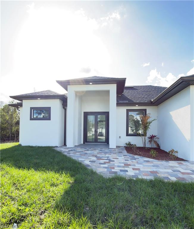 Back of house with french doors, a lawn, stucco siding, a patio area, and roof with shingles
