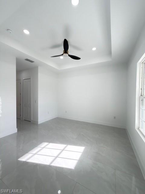 Unfurnished room featuring recessed lighting, ceiling fan, and a tray ceiling