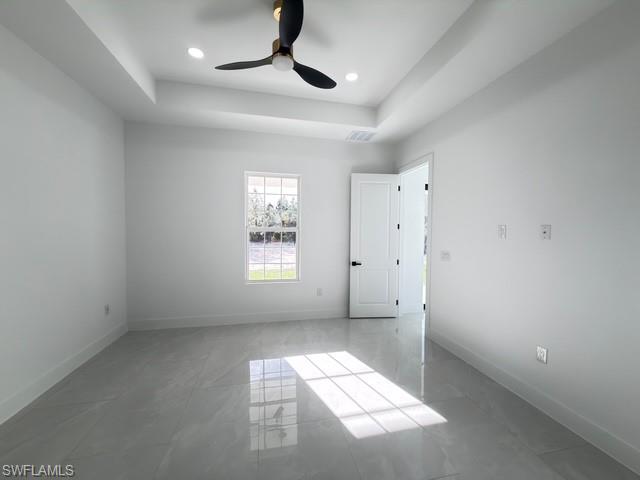 Unfurnished bedroom with a raised ceiling and a ceiling fan
