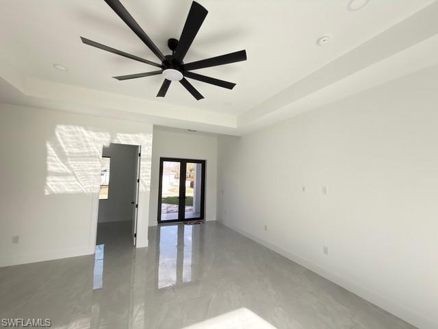 Empty room with french doors, a ceiling fan, and a raised ceiling