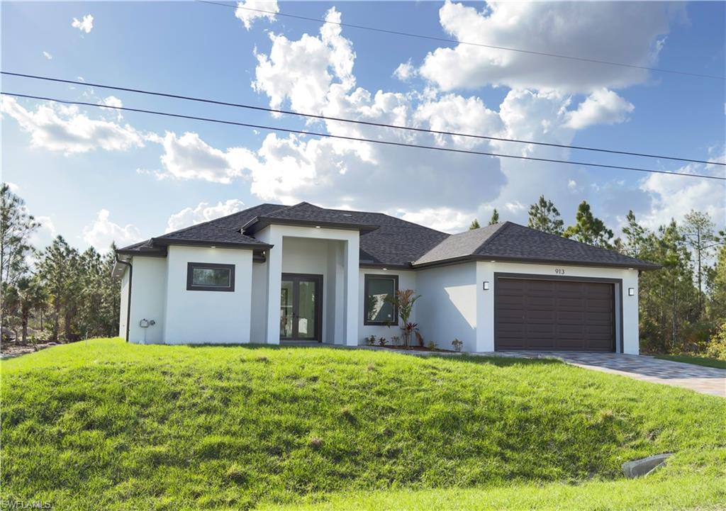 Prairie-style home with an attached garage, a front yard, driveway, and stucco siding