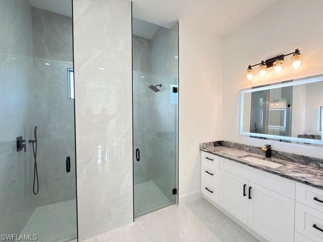 Full bathroom featuring a marble finish shower and vanity