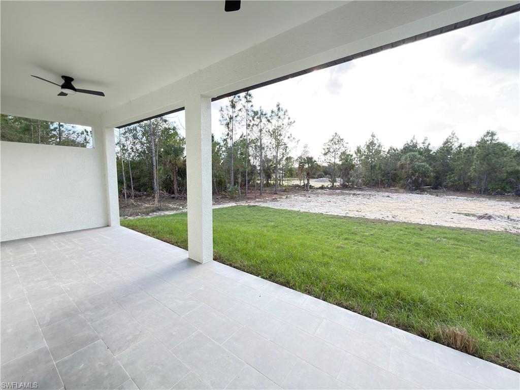 View of patio with a ceiling fan and view of wooded area
