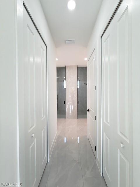 Hallway with light marble finish flooring and recessed lighting