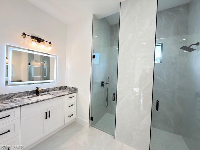 Full bath featuring vanity and a marble finish shower