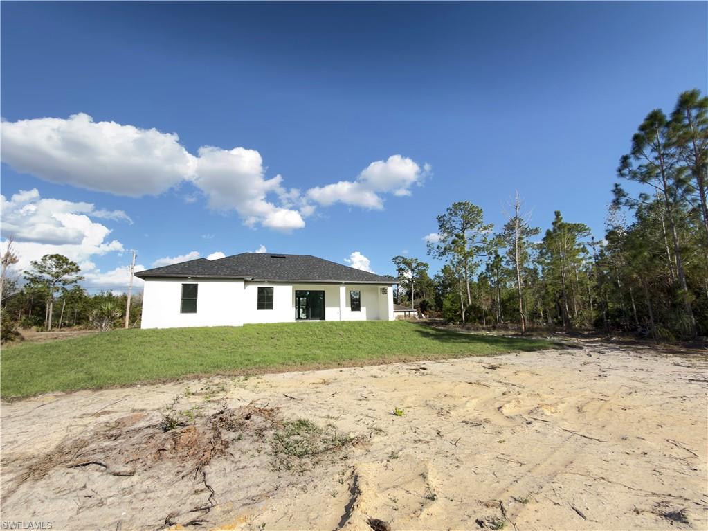 Rear view of house with a lawn, a patio area, and stucco siding