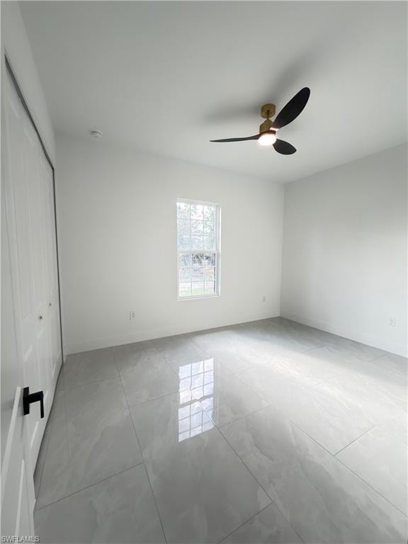 Unfurnished bedroom featuring a closet, ceiling fan, and light tile patterned floors