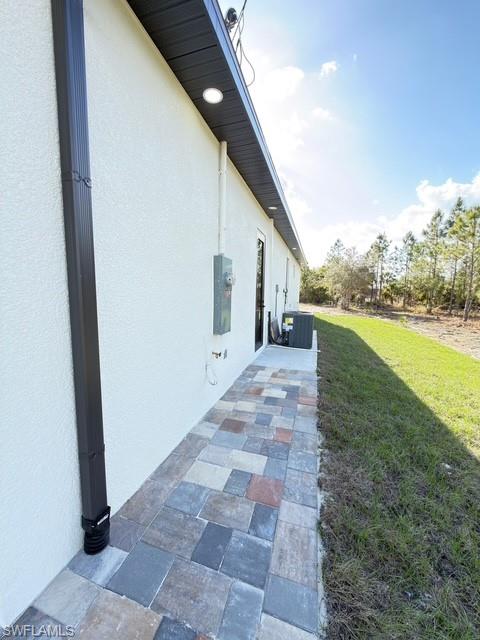 View of side of home with a lawn and stucco siding