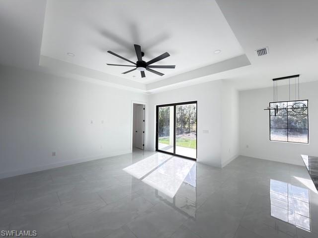 Empty room with ceiling fan and a tray ceiling