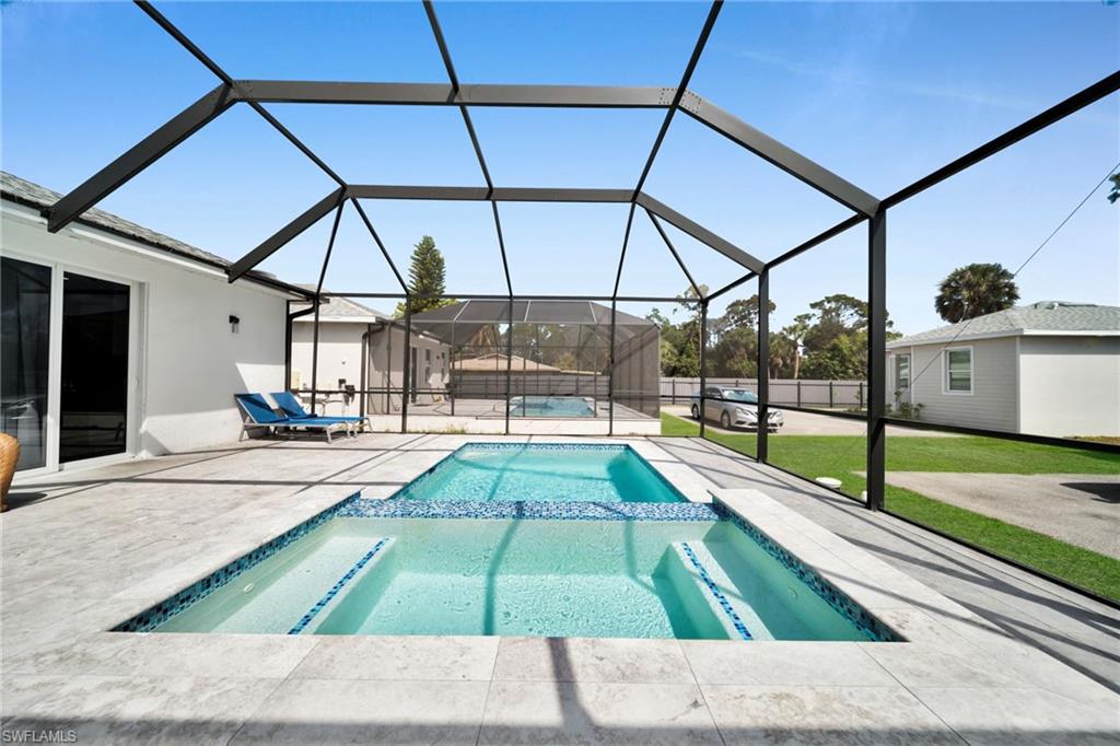 Integrated pool / spa with a sunroom, glass enclosure, a patio, and a lawn
