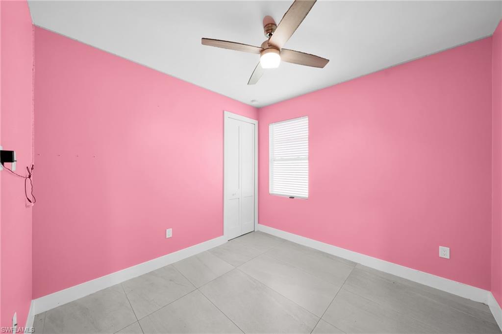 Empty room with ceiling fan and light tile patterned floors