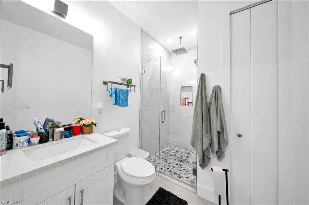 Bathroom featuring vanity, a marble finish shower, and recessed lighting