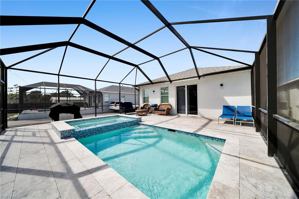Combined pool / hot tub with a sunroom, a lanai, and a patio area