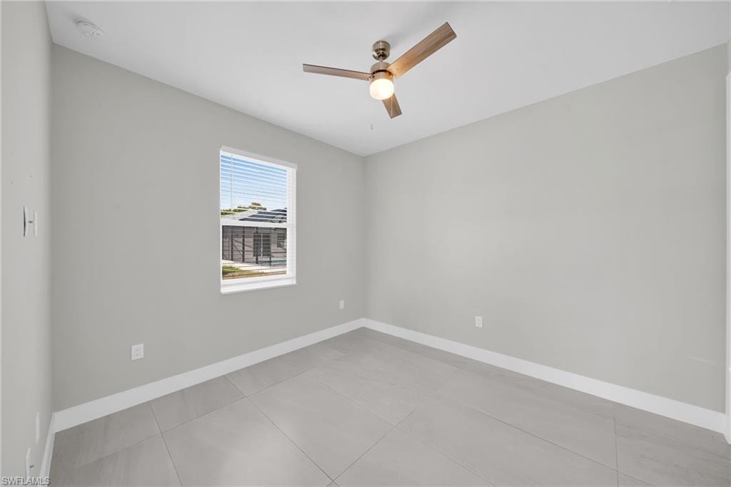 Empty room featuring a ceiling fan and light tile patterned floors