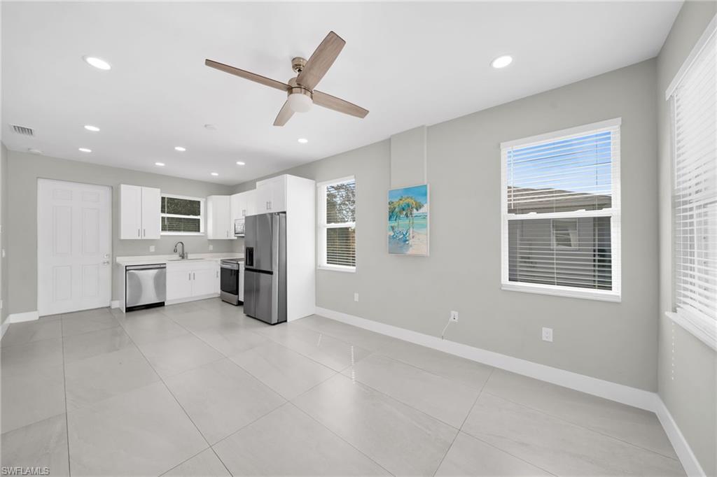 Kitchen featuring white cabinets, light countertops, a ceiling fan, stainless steel appliances, and healthy amount of natural light
