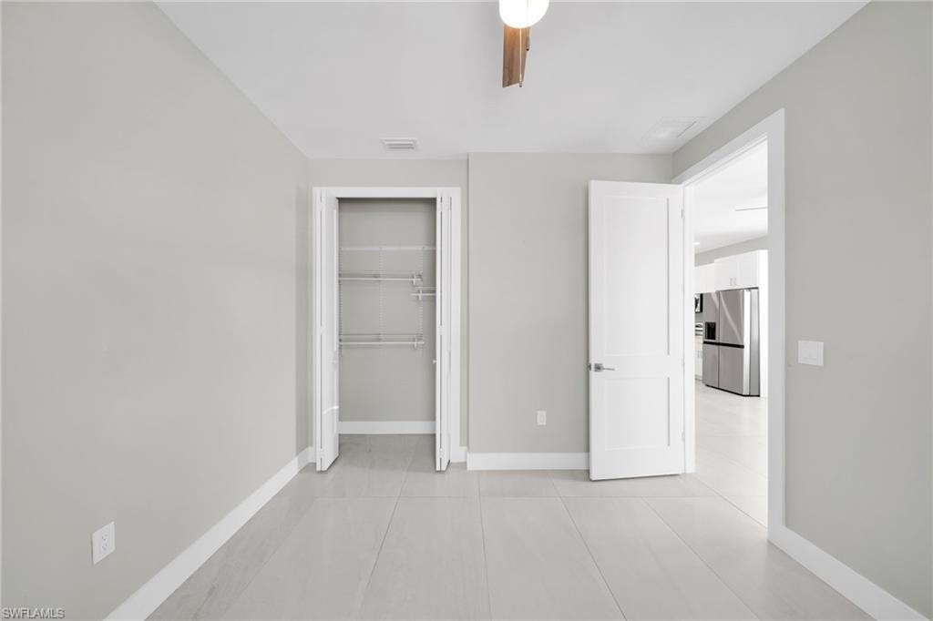 Unfurnished bedroom featuring stainless steel fridge, a closet, and ceiling fan