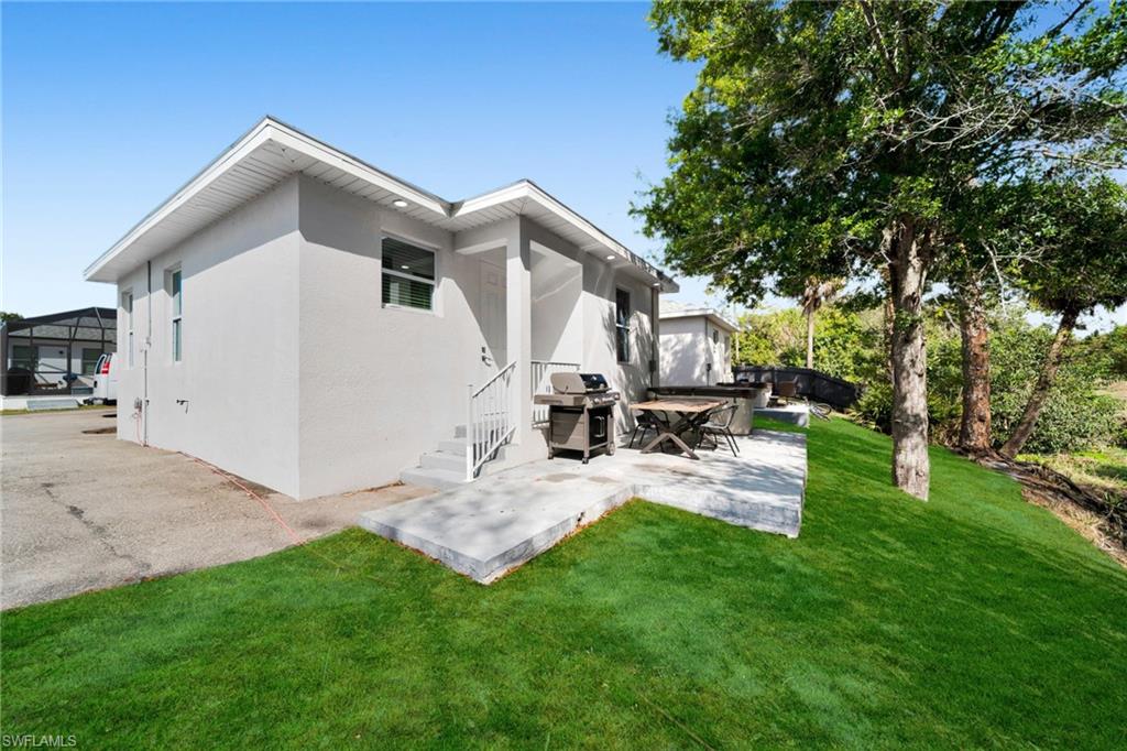 Rear view of house with stucco siding, a lawn, a patio area, and a deck