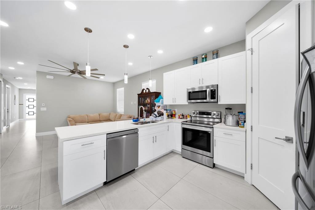 Kitchen featuring stainless steel appliances, a peninsula, healthy amount of natural light, and white cabinetry