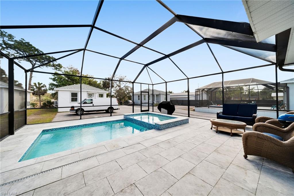 Integrated pool / spa featuring glass enclosure, a sunroom, a patio, a storage unit, and outdoor lounge area