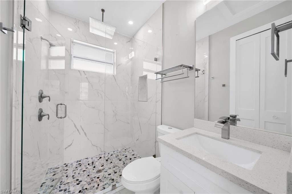 Full bath featuring vanity and a marble finish shower