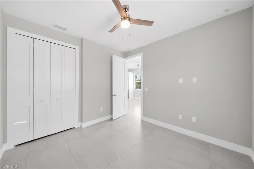 Unfurnished bedroom featuring a ceiling fan, a closet, and light tile patterned flooring