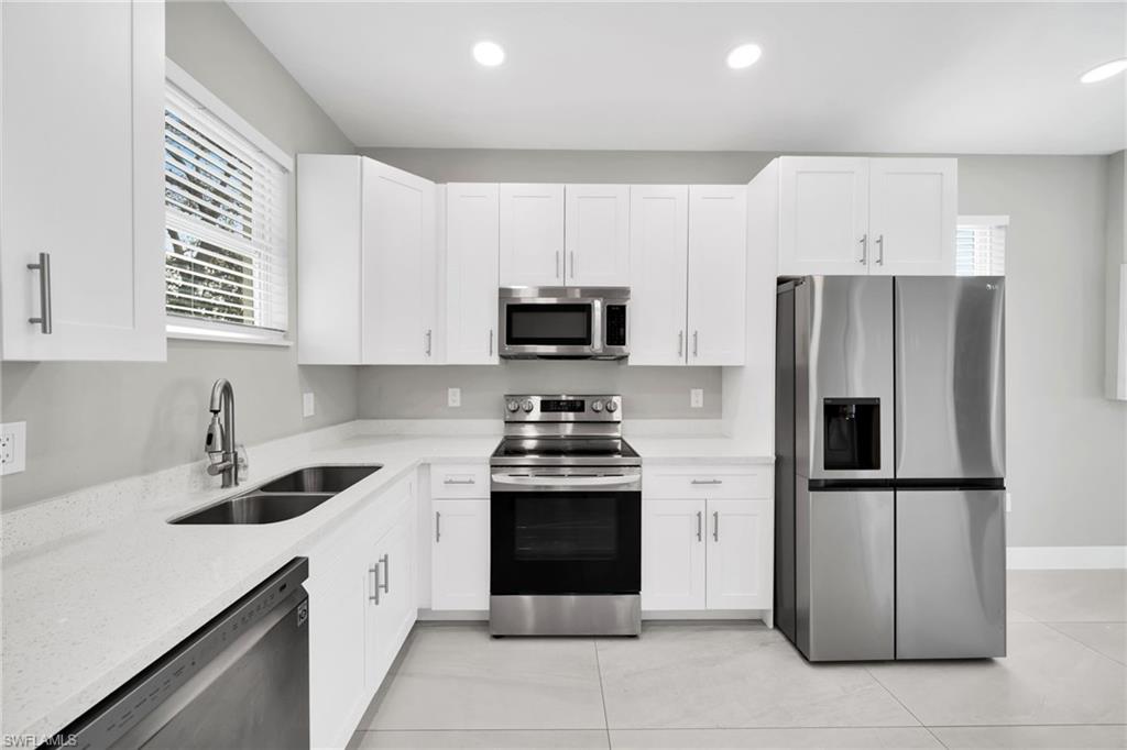 Kitchen featuring stainless steel appliances, light stone countertops, white cabinets, recessed lighting, and plenty of natural light