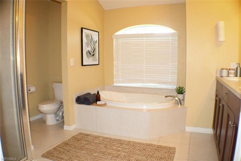 Full bath with vanity, light tile patterned flooring, a bath, and a stall shower