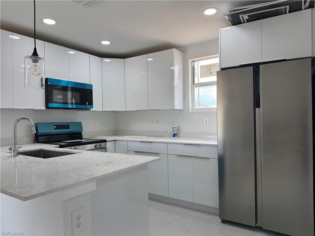 Kitchen featuring freestanding refrigerator, electric range, light stone counters, modern cabinets, and white cabinetry