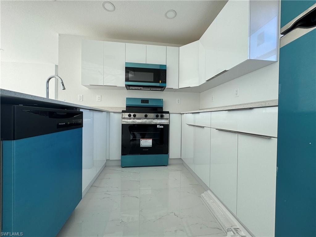 Kitchen featuring stainless steel appliances, white cabinets, light marble finish floors, modern cabinets, and light stone countertops