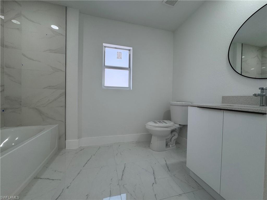 Bathroom with vanity, light marble finish flooring, and a combined bath / shower with marble appearance