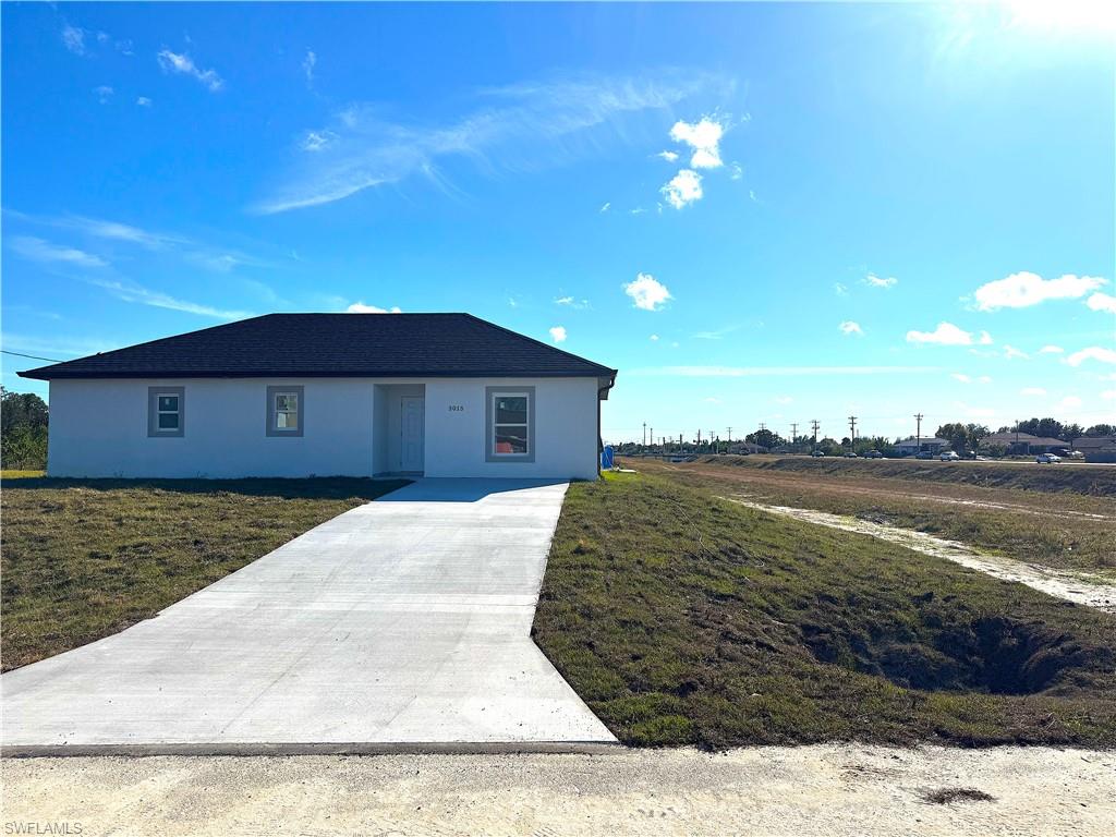 Ranch-style home featuring stucco siding, driveway, and a front yard
