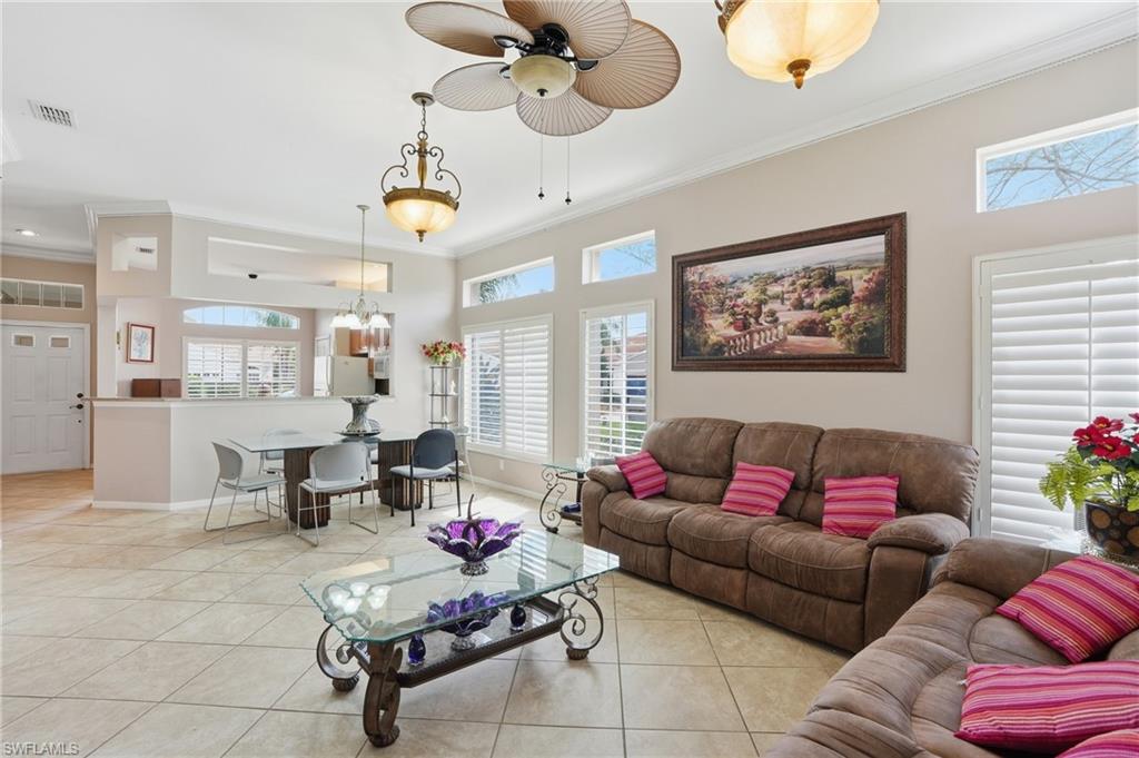 Living area with crown molding, a ceiling fan, light tile patterned floors, and hanging lights