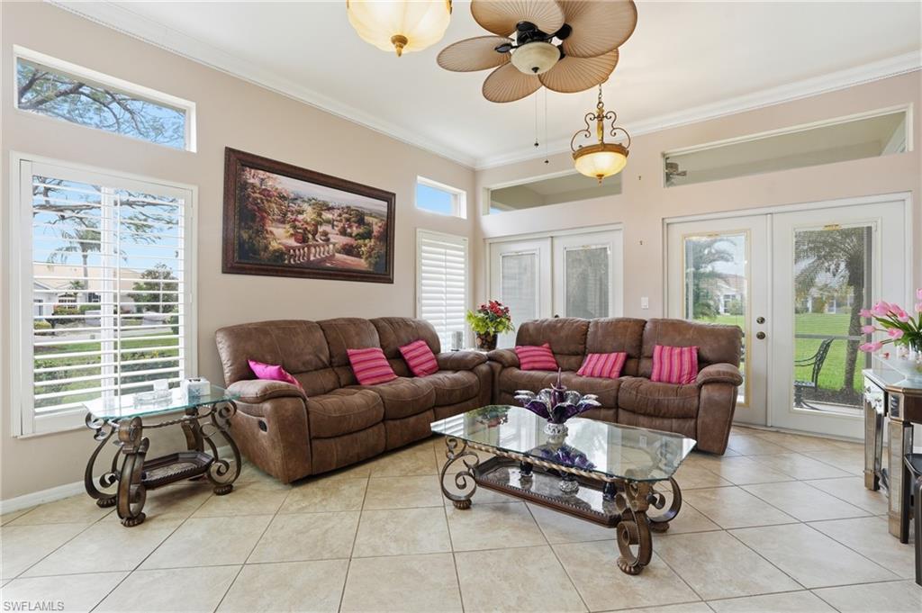 Living area with french doors, crown molding, healthy amount of natural light, and light tile patterned flooring