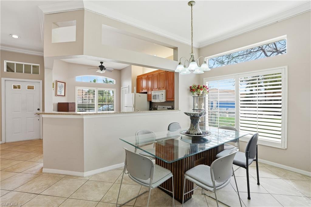 Dining space featuring crown molding, a ceiling fan, hanging lights, and light tile patterned flooring