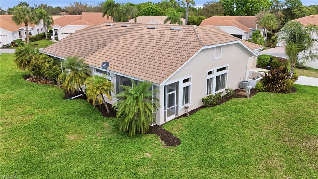 Rear view of property with a tiled roof, a sunroom, a yard, and stucco siding
