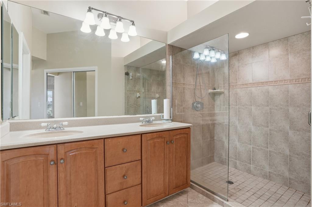 Full bathroom featuring double vanity, a shower stall, and light tile patterned flooring