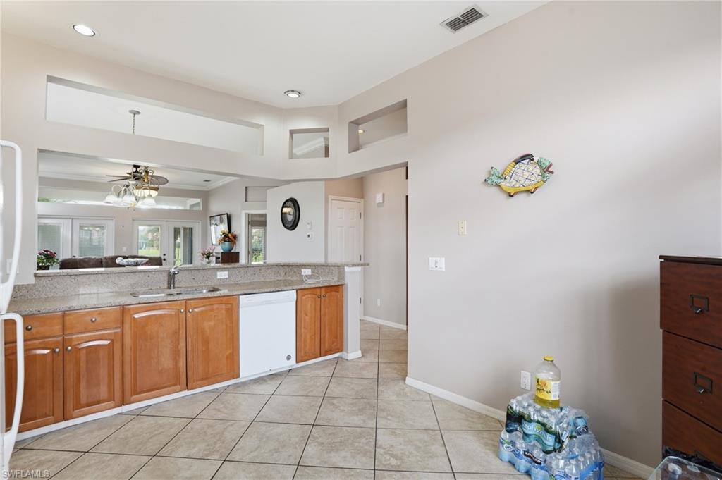 Kitchen with light stone countertops, french doors, white appliances, and wood finish cabinetry