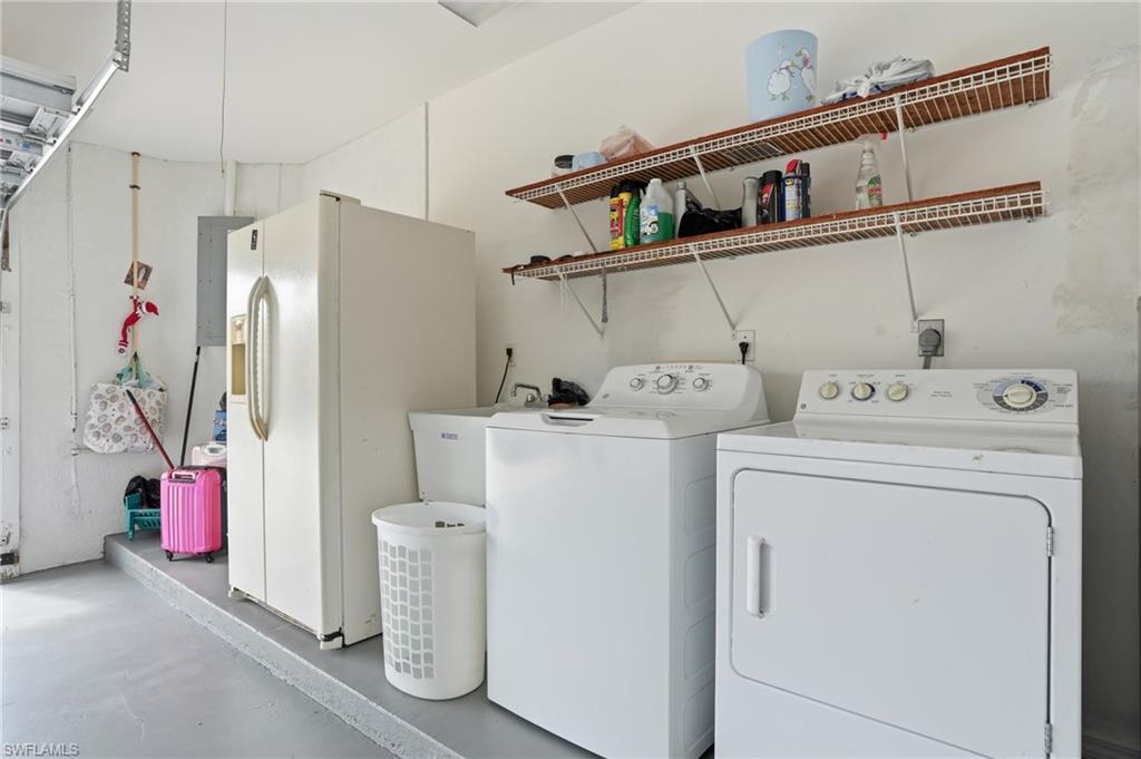 Laundry room with finished concrete floors, washing machine and dryer, and electric panel