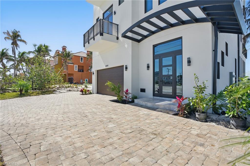 Entrance to property featuring stucco siding, french doors, a garage, and decorative drivewayVirtually Enhanced