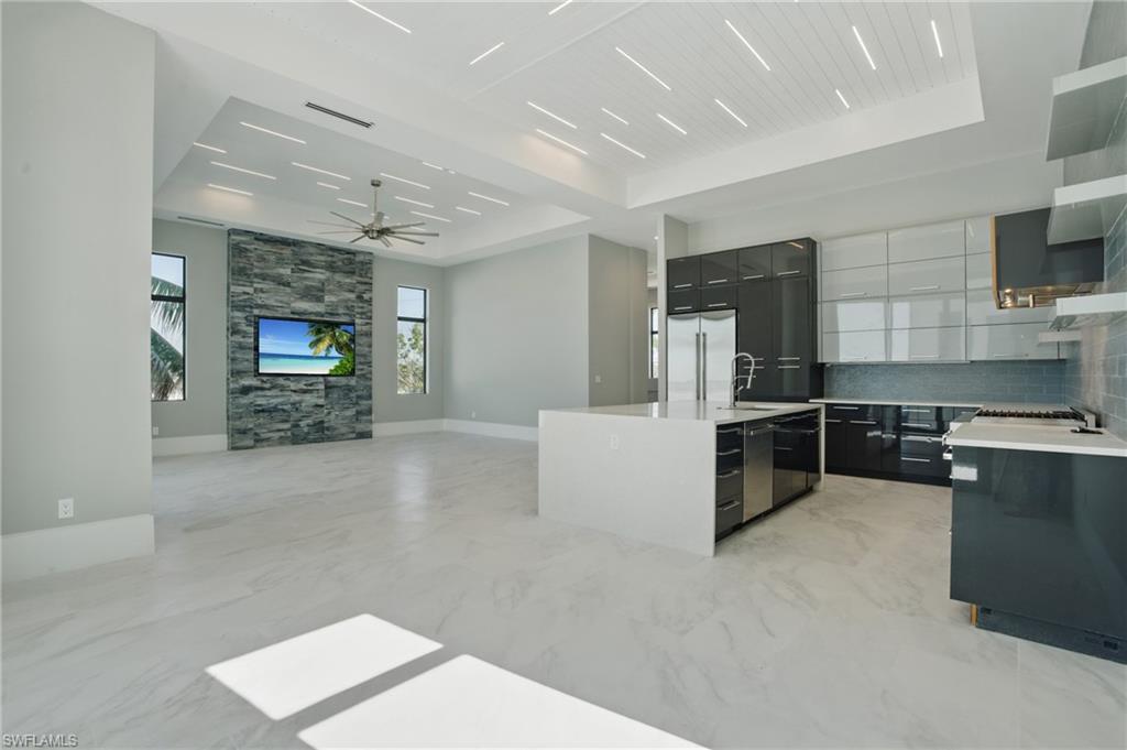 Kitchen with light marble finish floors, modern cabinets, a center island, stainless steel appliances, and light stone countertops Virtually Enhanced