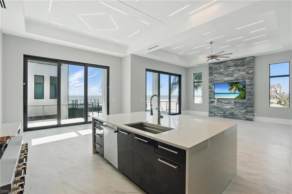 Kitchen featuring an island with sink, dark cabinetry, open floor plan, a tray ceiling, and modern cabinets Virtually Enhanced