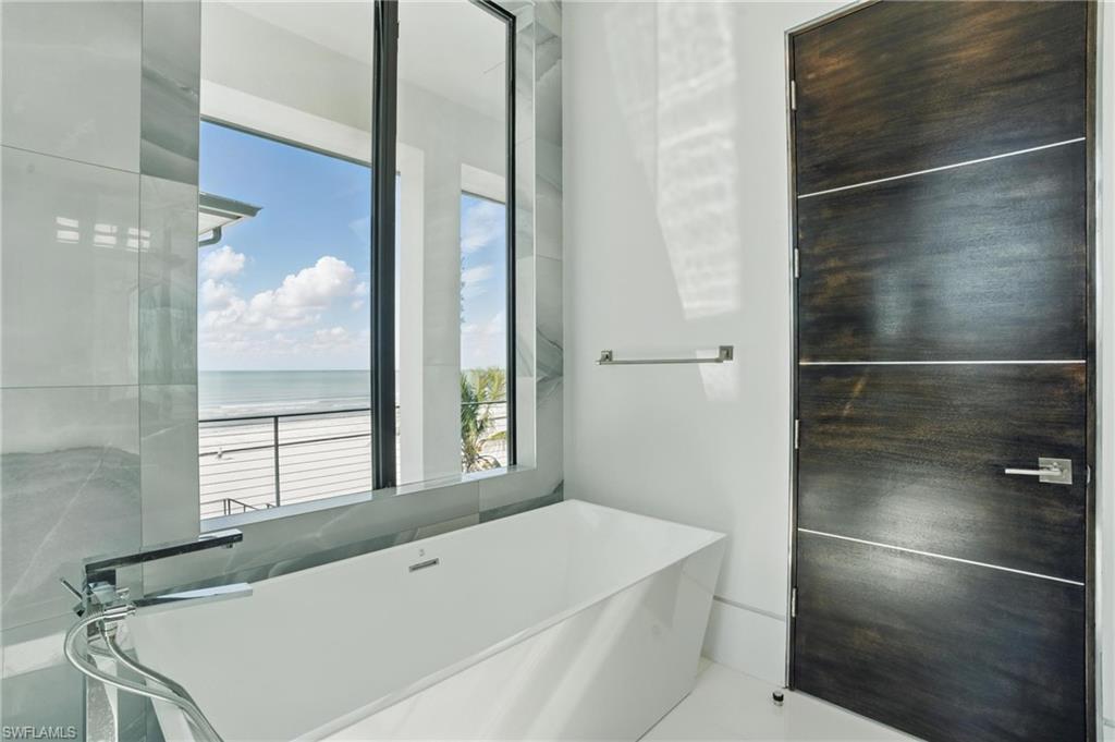 Bathroom with a freestanding tub and a water view Virtually Enhanced