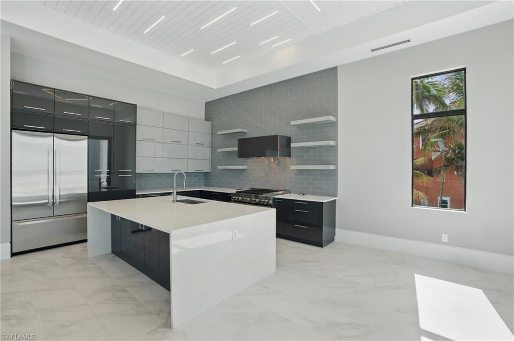 Two tone kitchen with modern cabinets, open shelves, stainless steel appliances, light marble finish floors, and dual tone cabinets Virtually Enhanced