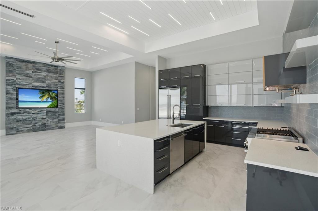 Kitchen with modern cabinets, a kitchen island with sink, a raised ceiling, stainless steel appliances, and two tone color scheme Virtually Enhanced