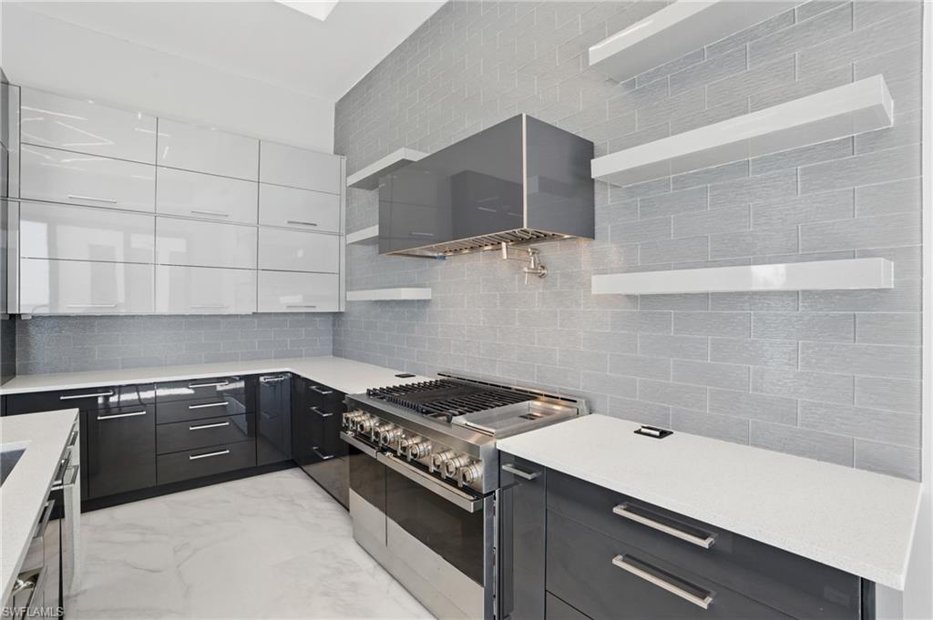 Two tone kitchen with double oven range, two tone cabinets, open shelves, light stone counters, and light marble finish flooring Virtually Enhanced