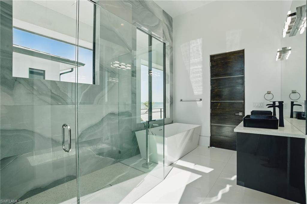 Full bathroom featuring vanity, a freestanding bath, plenty of natural light, and a marble finish shower Virtually Enhanced