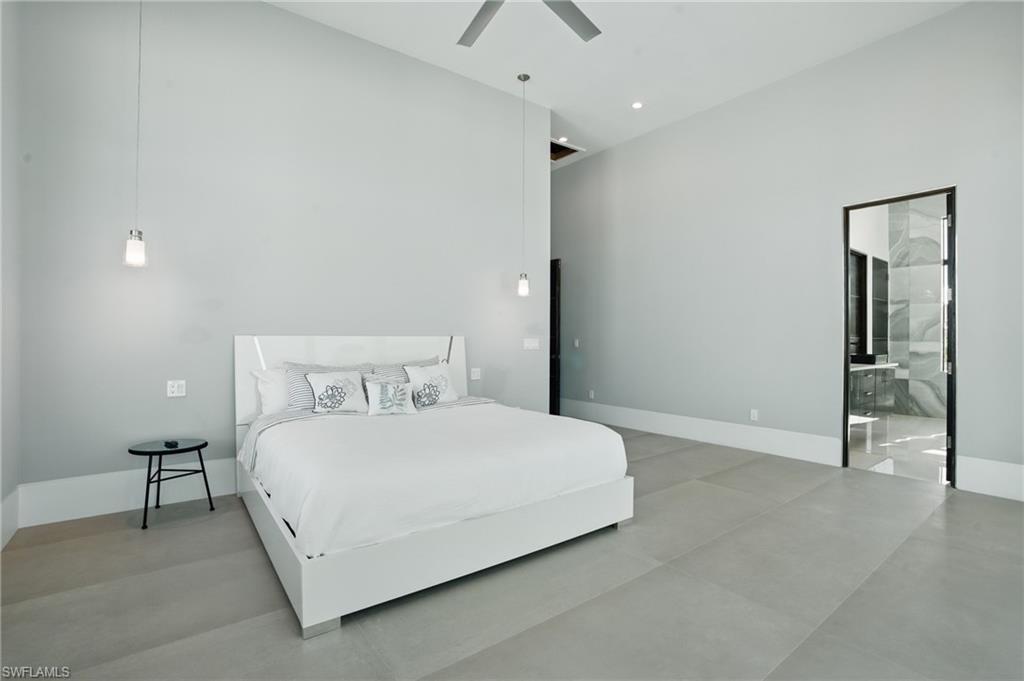 Bedroom featuring a high ceiling, a ceiling fan, and connected bathroom Virtually Enhanced