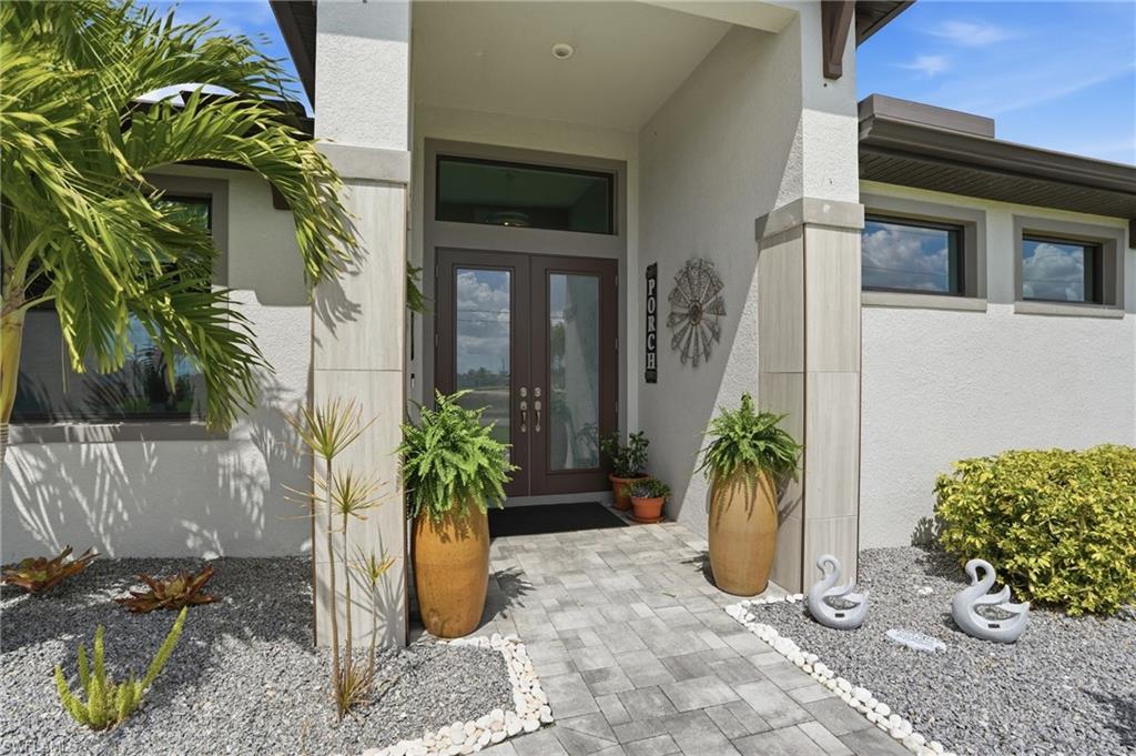 View of exterior entry featuring glass doors and stucco siding