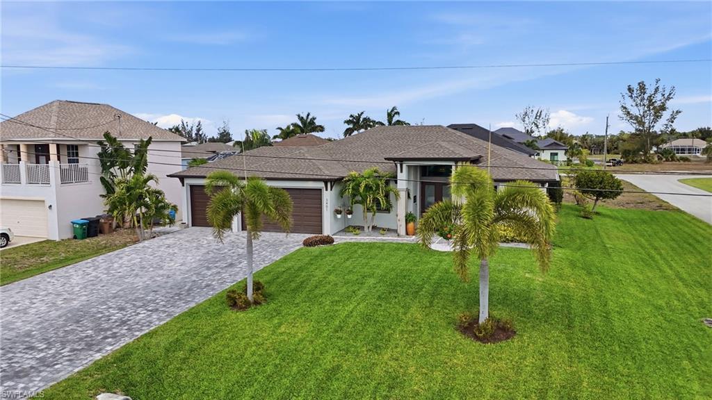 View of front of property featuring decorative driveway, a front yard, an attached garage, a residential view, and stucco siding