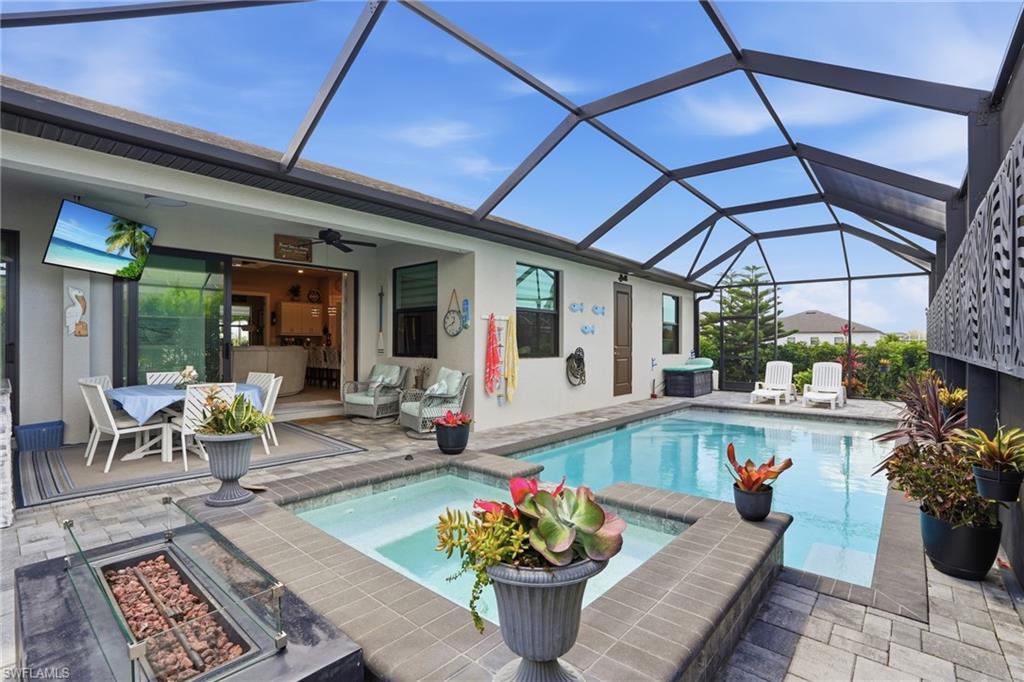 Combined pool / hot tub featuring a fire pit and screen enclosure
